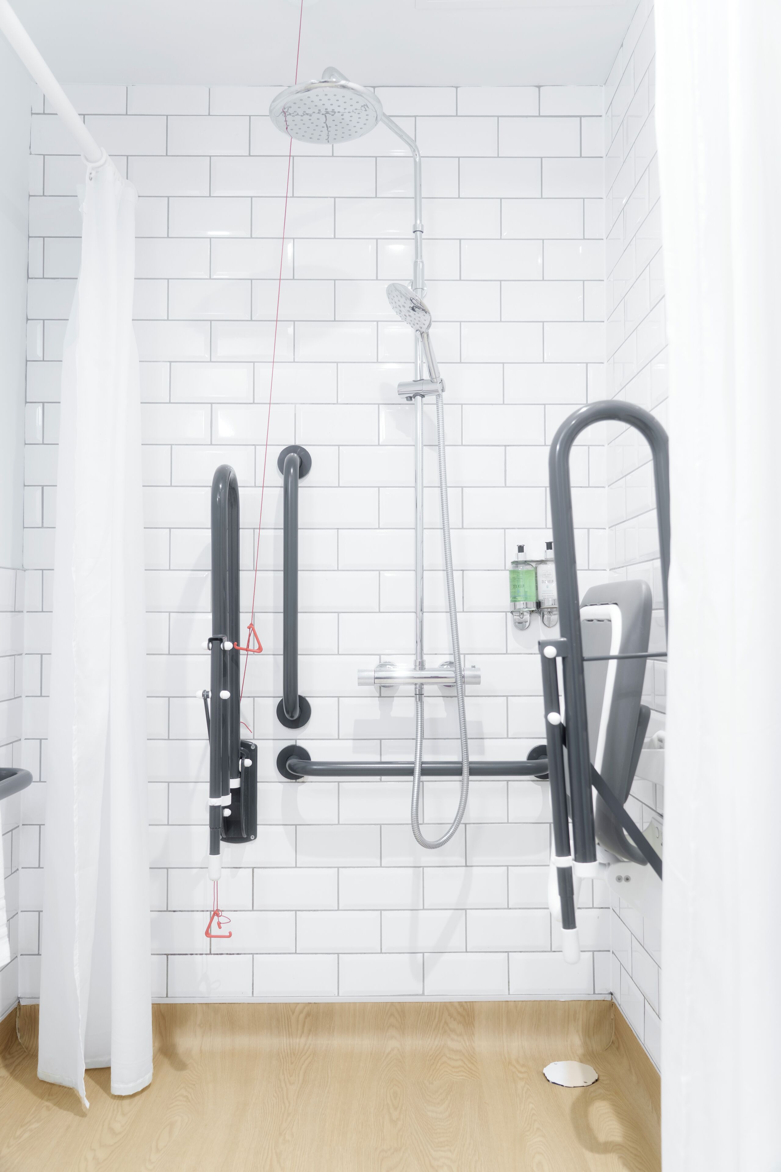 A modern shower with a handheld showerhead, a handheld shower attachment, and a wall-mounted faucet.