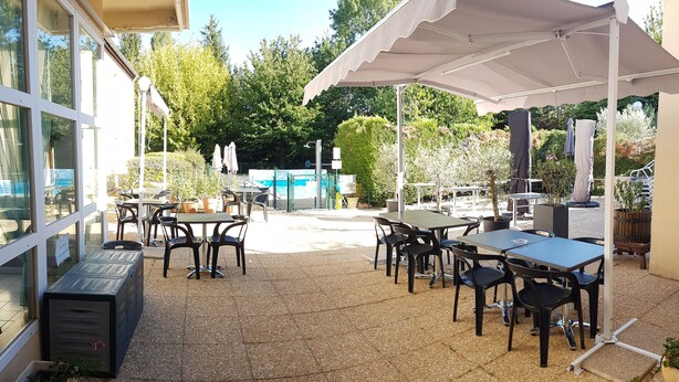 An outdoor patio with tables and chairs, umbrellas, and a pool in the background. - Hôtel la Bérangère (Perouges)