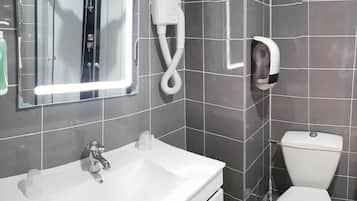 A bathroom with a white sink, a mirror, a hairdryer, and a toilet.
