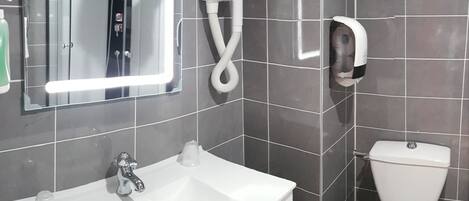 A bathroom with a white sink, a mirror, a hairdryer, and a toilet.