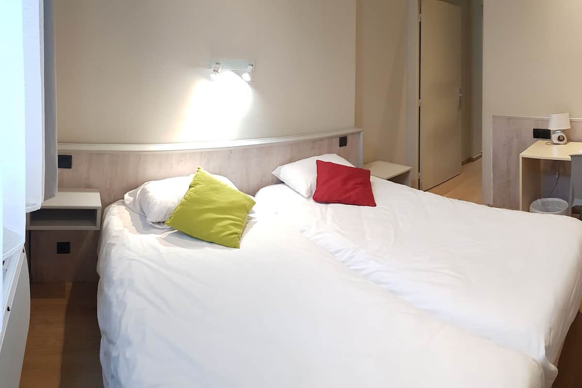 Une chambre d’hôtel avec un lit, un bureau et une chaise.
