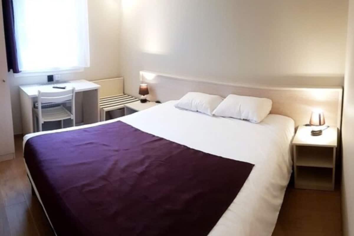Une chambre d’hôtel avec un grand lit, un bureau et une chaise.