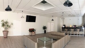 A spacious lobby with a modern design, featuring a sectional sofa, a glass-top coffee table, and a reception area with a counter and chairs. - Hôtel la Bérangère (Perouges)