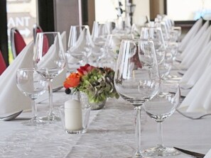 Une table dressée pour le dîner, avec plusieurs verres à vin et un centre de table composé de fleurs.