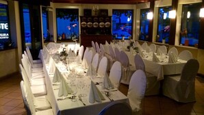 Een balzaal met lange tafels gedekt voor een formeel evenement, met witte tafelkleden en stoelen.