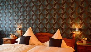 Une chambre à coucher avec un papier peint à motifs, une tête de lit en bois et des lampes de chevet.