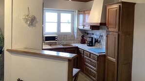 Una cocina con armarios de madera, microondas, lavaplatos y ventana.