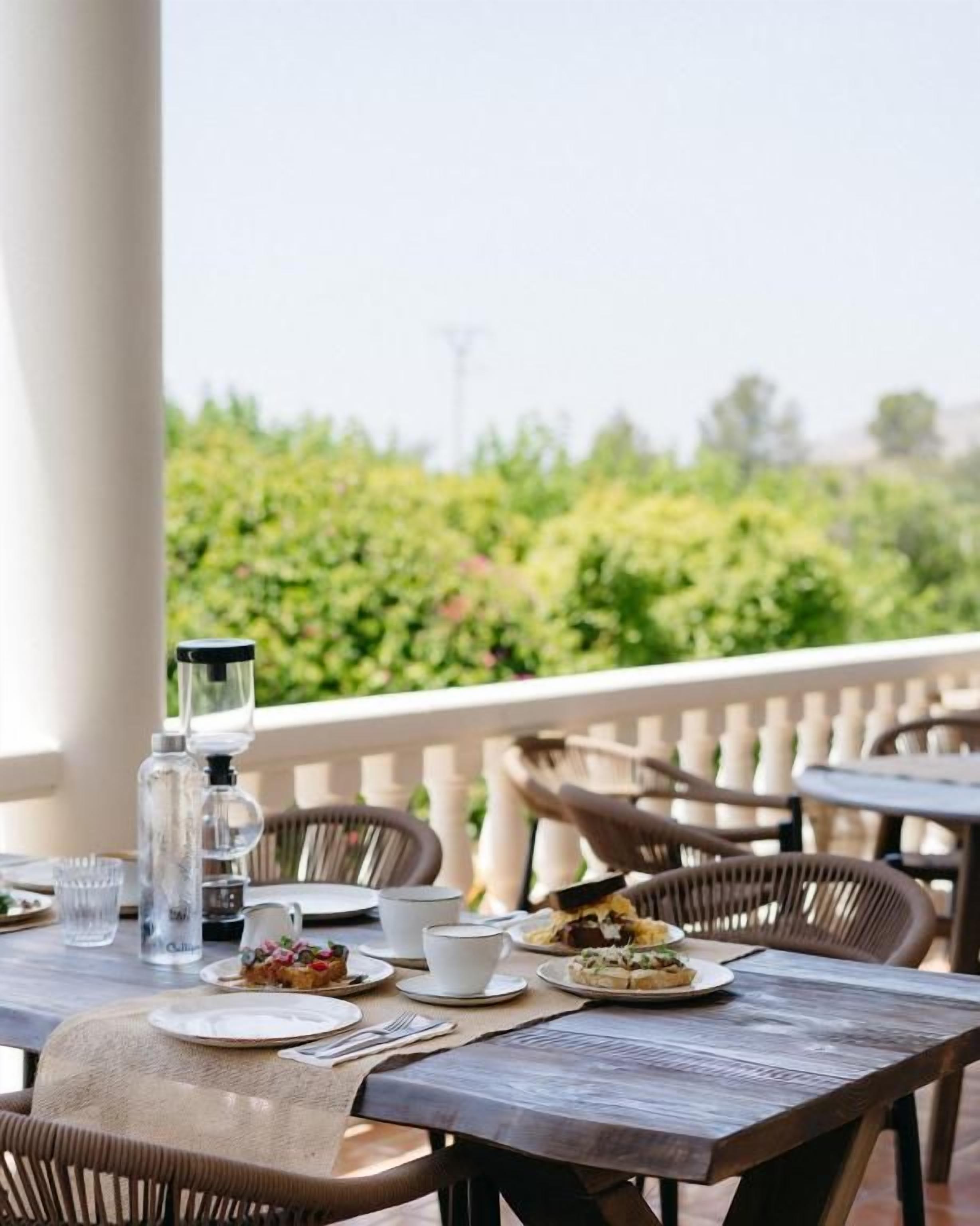 An outdoor dining area with tables, chairs, and a view of greenery.