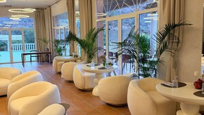 Un área de estar moderna con asientos redondos, ventanas amplias y plantas de interior.