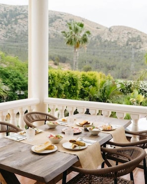 An outdoor dining area with a table set for two, surrounded by wicker chairs, overlooking a mountainous landscape. - Boutique Hotel La Plantación  (Finestrat)