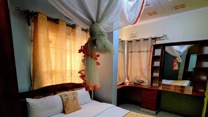 Un dormitorio con cama, mesita de noche, espejo y cortinas.