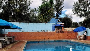 Piscina con bordes de azulejos y zona circundante con mesas y sillas.