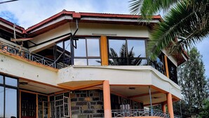 Un edificio de varios pisos con una escalera que lleva a la entrada, un balcón y un vehículo estacionado cerca.