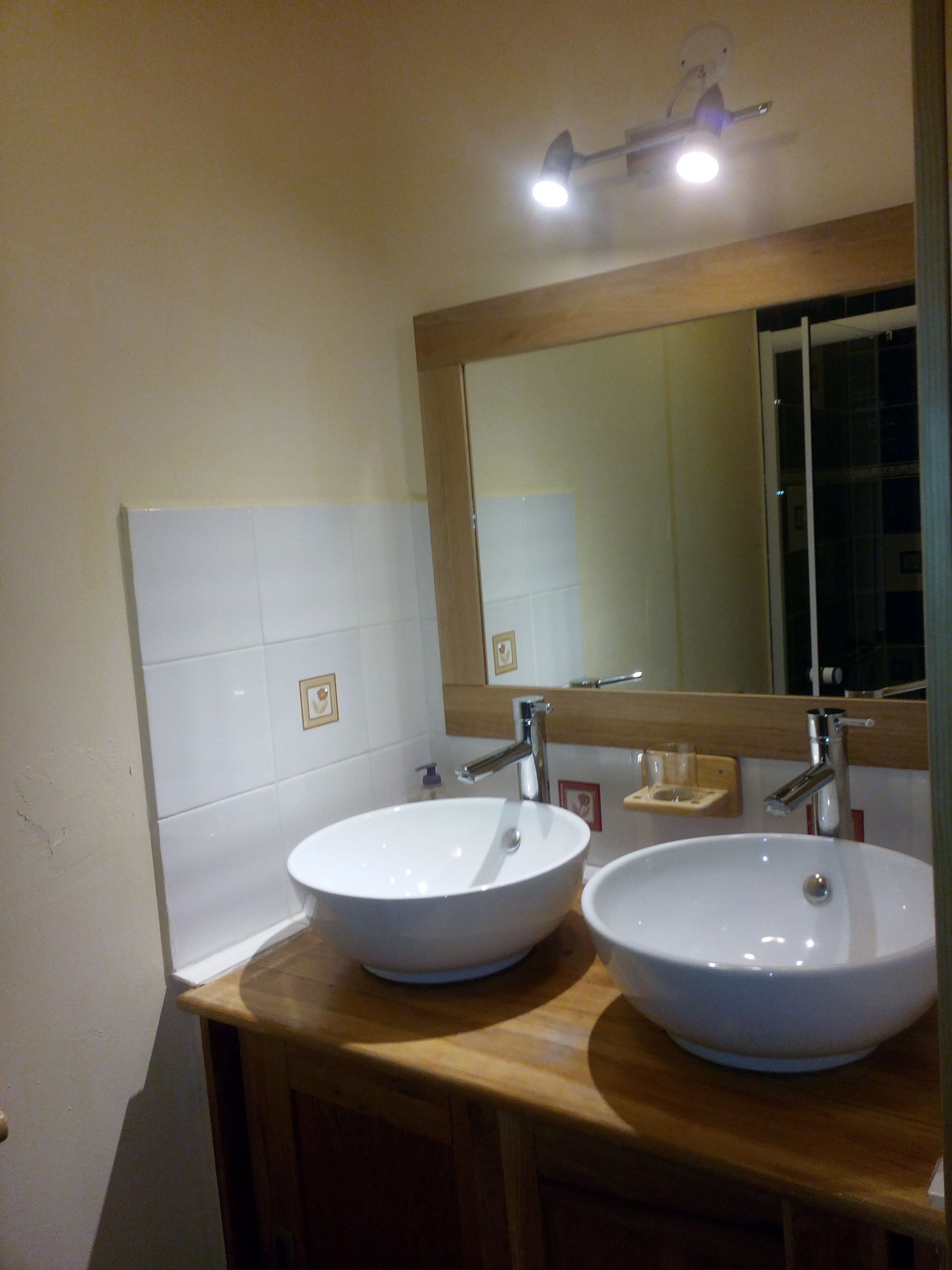 A bathroom with two white sinks, a wooden countertop, a mirror, and a ceiling light.