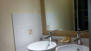 A bathroom with two white sinks, a wooden countertop, a mirror, and a ceiling light.