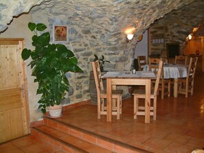 Un coin repas rustique avec des murs en pierre, des meubles en bois et une plante en pot.