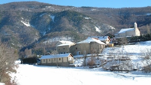 Un villaggio innevato con edifici in pietra e una chiesa su una collina.