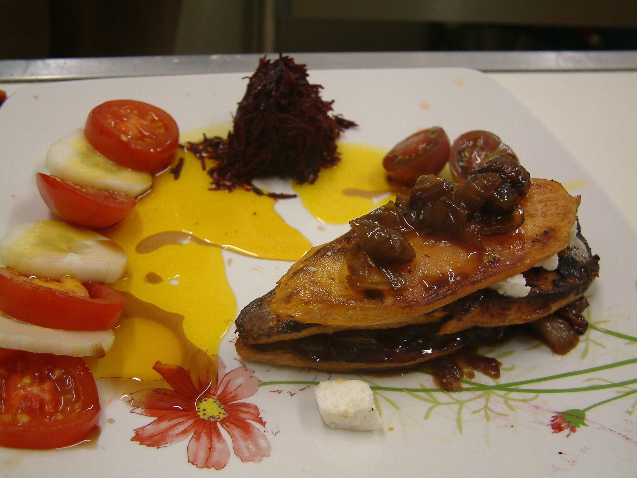 A plate with a grilled chicken breast, cherry tomatoes, and a side of what appears to be beetroot salad.