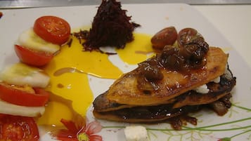 A plate with a grilled chicken breast, cherry tomatoes, and a side of what appears to be beetroot salad.
