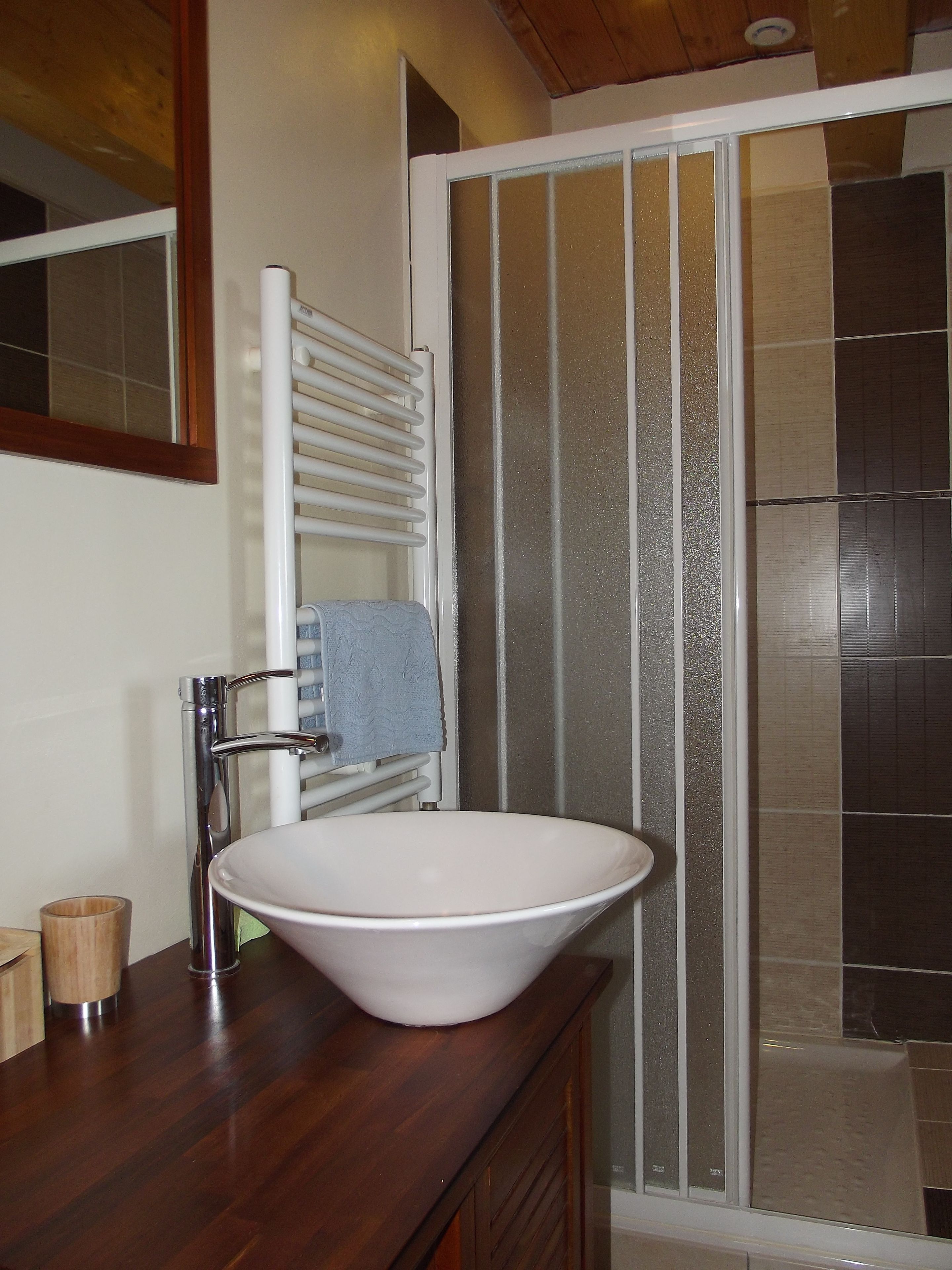 A bathroom with a white sink, wooden countertop, and a glass shower enclosure.