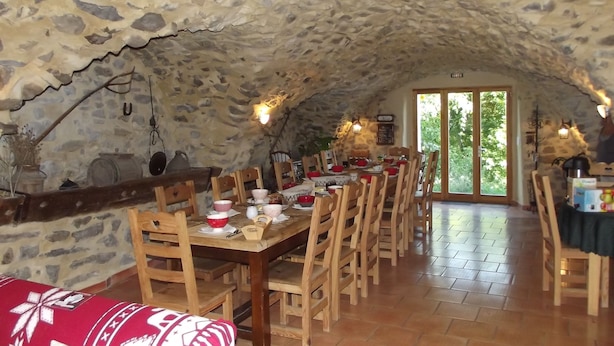 Un'area pranzo rustica con pareti in pietra, arredi in legno e vista sul verde circostante.