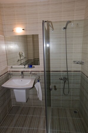 A bathroom with a glass-enclosed shower, a sink, and a mirror. - Grand Montana (Bansko)