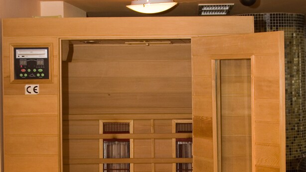 A sauna with a control panel, wooden panels, and a glass door. - Grand Montana (Bansko)