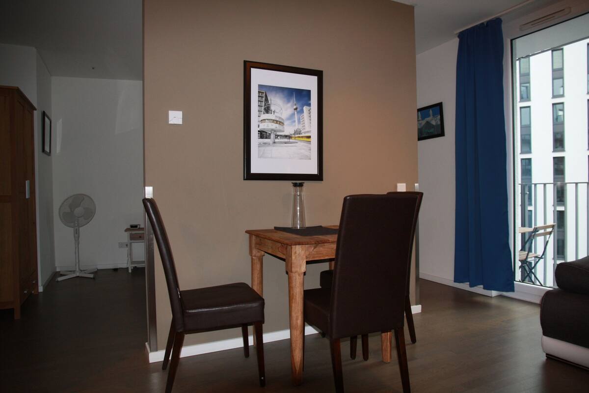 Ein Essbereich mit Tisch und Stühlen, ein gerahmtes Bild an der Wand und ein Ausblick durch ein Fenster.