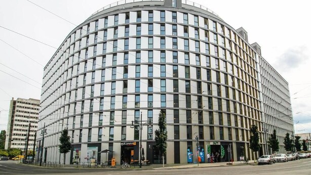 A modern, circular building with a glass facade, likely a hotel or office building. - Holiday at Alexanderplatz Apartments (Berlin)