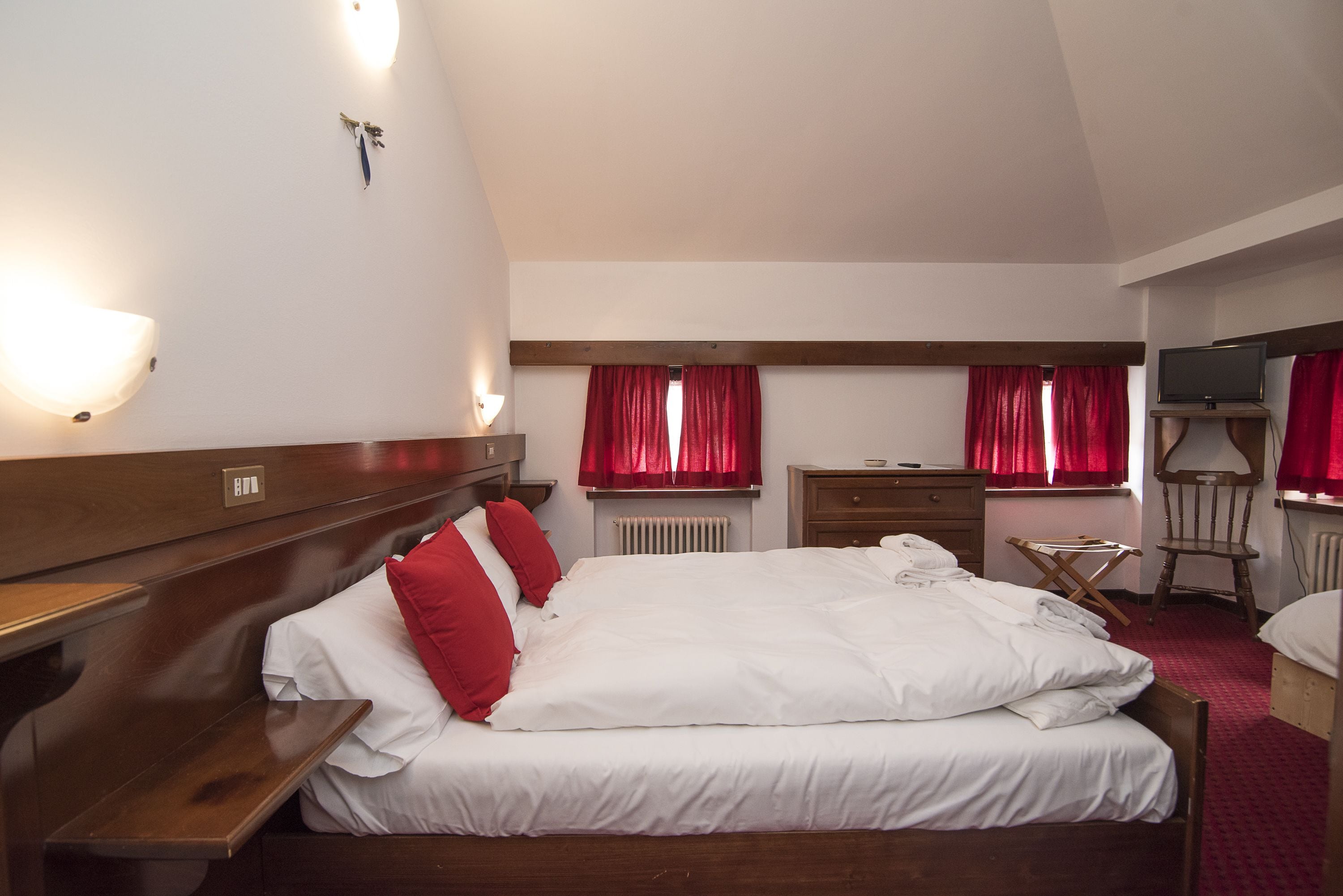 Een hotelkamer met een groot bed, een houten hoofdbord, nachtkastjes, een dressoir, een stoel en een televisie.