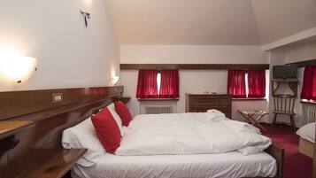 Een hotelkamer met een groot bed, een houten hoofdbord, nachtkastjes, een dressoir, een stoel en een televisie.