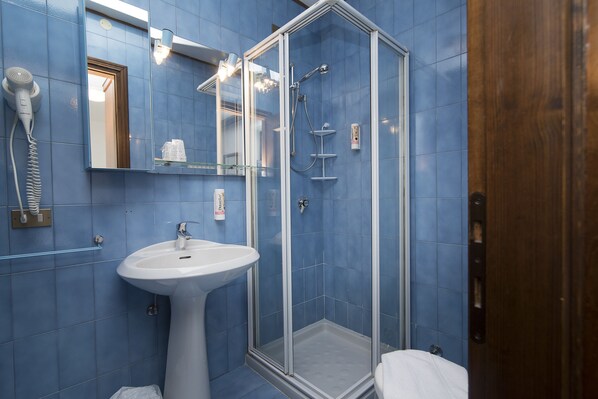 A bathroom with a white sink, a glass-enclosed shower, and a mirror above the sink. - Locanda ai Dogi (Pieve di Cadore)