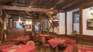 A restaurant with wooden beams, red tablecloths, and patterned chairs. - Locanda ai Dogi (Pieve di Cadore)