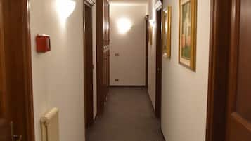 A narrow hallway with wooden doors, a radiator, and framed pictures on the walls.