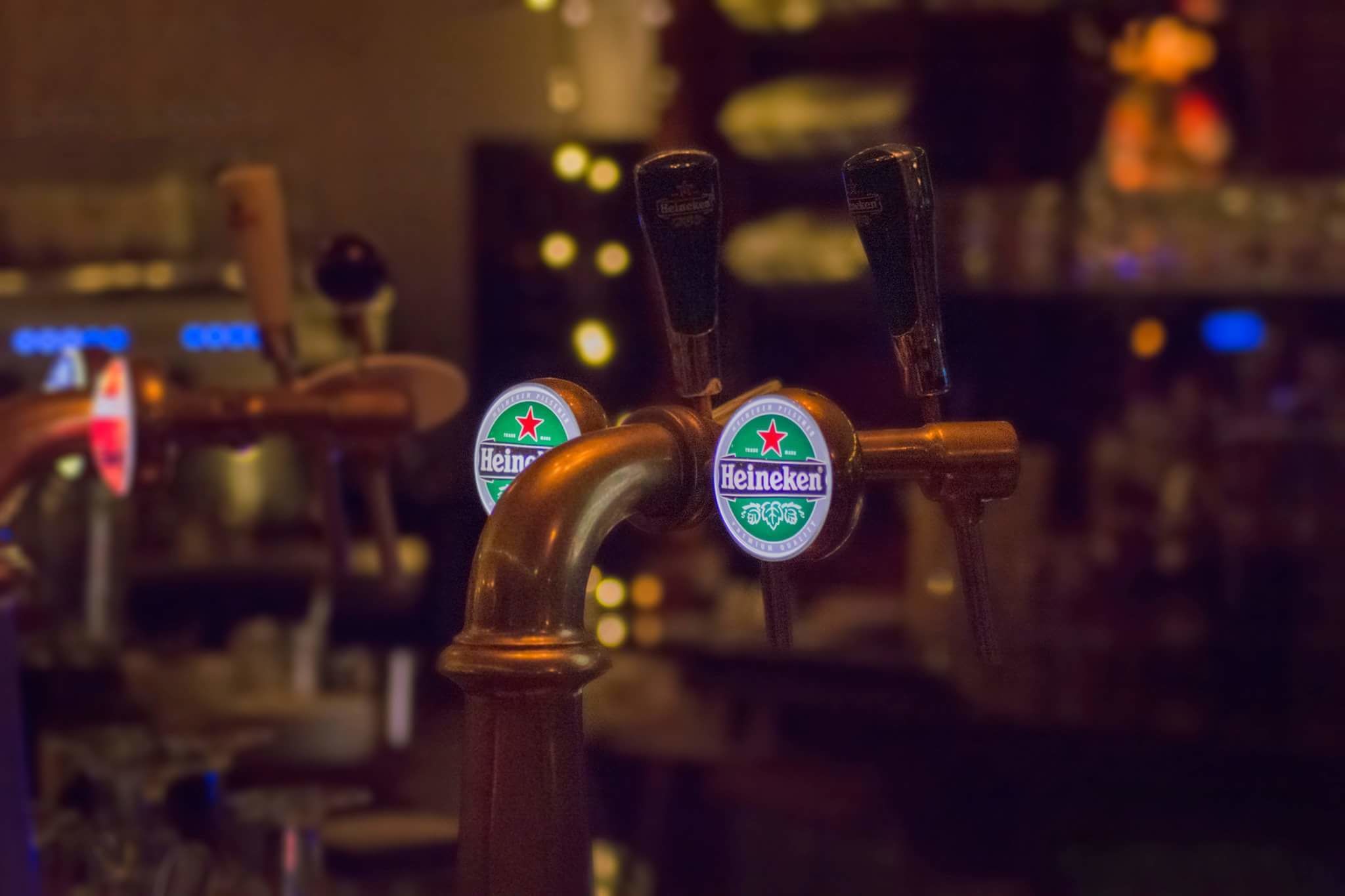 A bar with multiple beer taps, including Heineken.