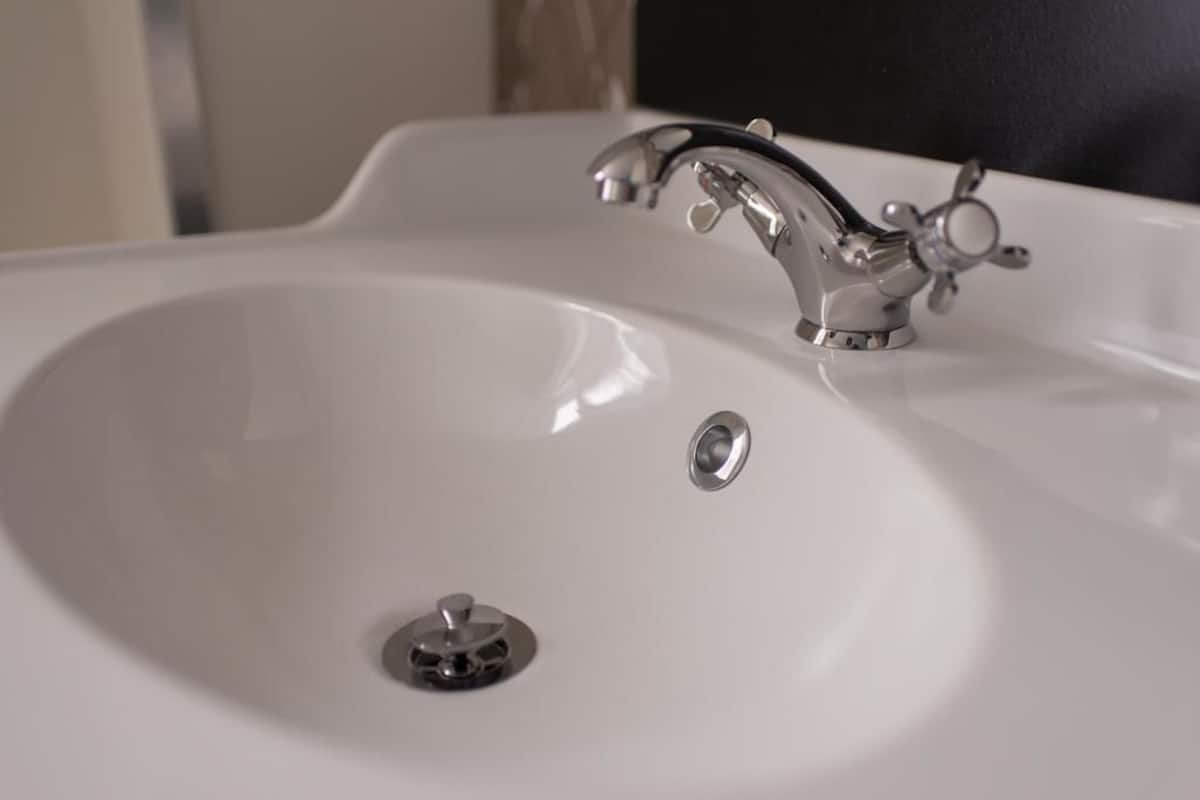 A white bathroom sink with a chrome faucet and a drain.