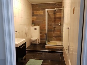 A modern bathroom with a glass-enclosed shower, a white toilet, and a sink. - Cafe pension The Chandelier (Terneuzen)