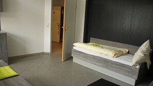 A modern bedroom with a bed, a bedside table, and a door leading to another room. - Komfort Apartments am Marktplatz (Bexbach)