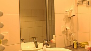 A bathroom with a round sink, a mirror, a hairdryer, and a towel rack. - Komfort Apartments am Marktplatz (Bexbach)