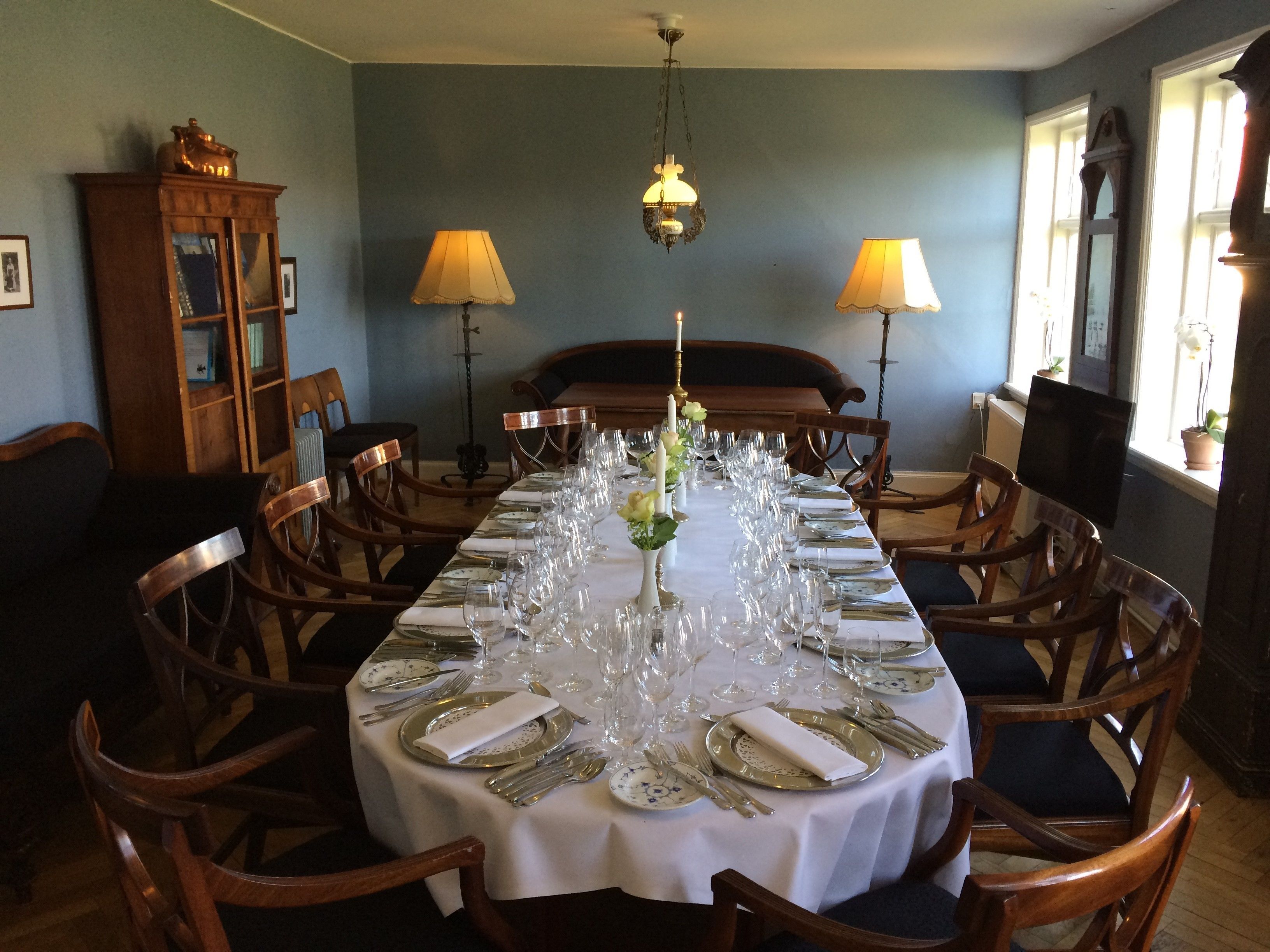 A dining room with a long table set for a meal, surrounded by wooden chairs.