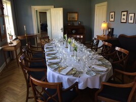 Un comedor formal con una larga mesa dispuesta para una comida, rodeada de sillas de madera.