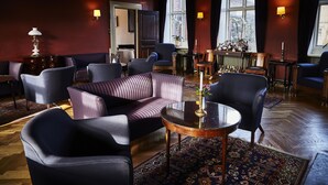 A room with a sofa, chairs, a table, and a potted plant. - Brøndums Hotel (Skagen)