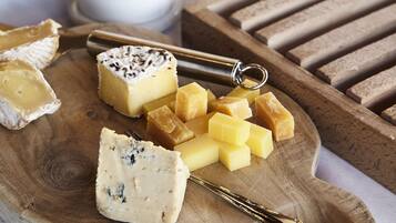 Una tabla de madera con varios quesos y un cuchillo para queso.