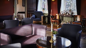 A room with striped sofas, a round table with a candle, and a bar area with bottles. - Brøndums Hotel (Skagen)