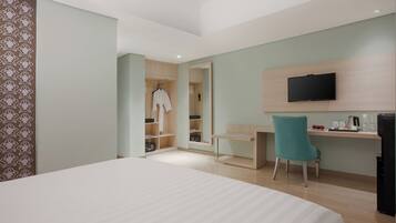 A hotel room with a bed, a desk, a chair, a TV, and a wardrobe.