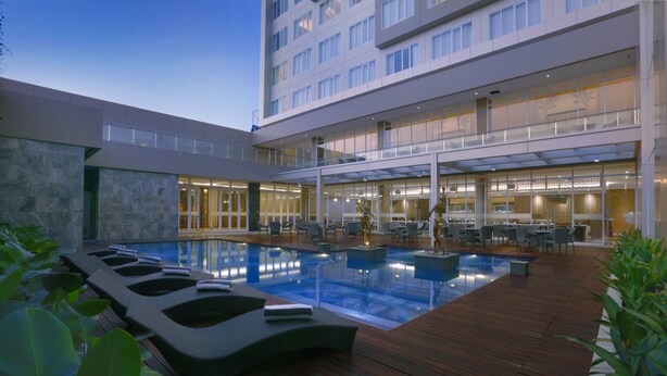 Ett modernt hotell med en pool på takterrassen, utomhusmöbler och en matplats.