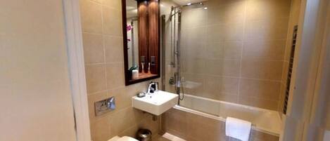 A modern bathroom with a glass-enclosed shower, a white sink, and a mirror above the sink.