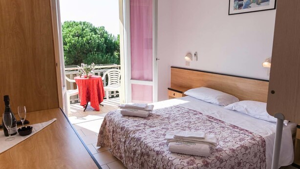 Una habitación de hotel con cama, mesita de noche, ventana y vistas al exterior.