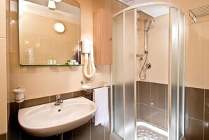 Un baño con lavamanos, espejo y ducha.