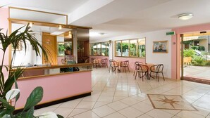 Vestíbulo de hotel con mostrador de recepción, varias zonas de estar y grandes ventanales que ofrecen vistas al exterior.